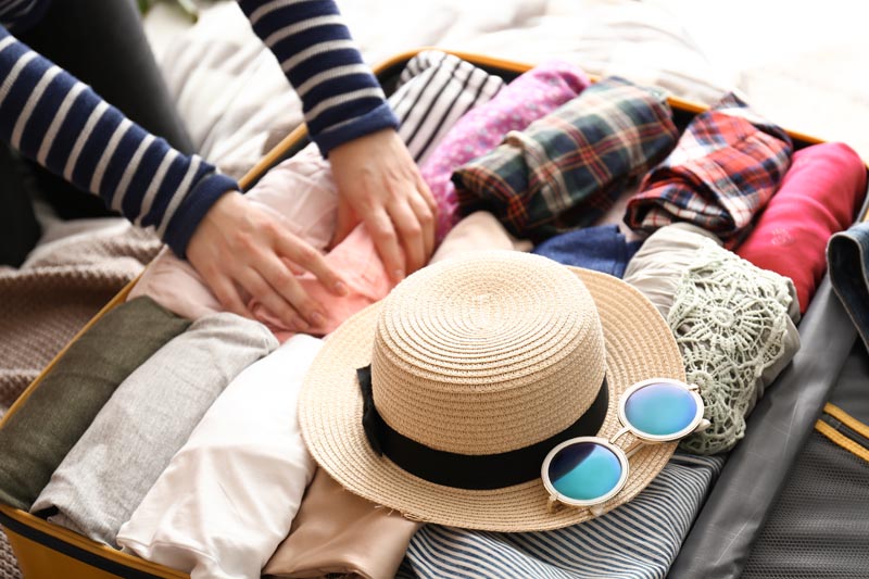 Young woman packing suitcase at home